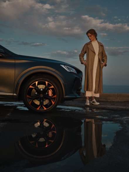 woman-standing-next-to-the new CUPRA Formentor  with brembo brakes and alloy wheels in copper