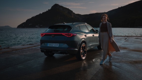 woman standing next to the new cupra formentor suv with full led lights